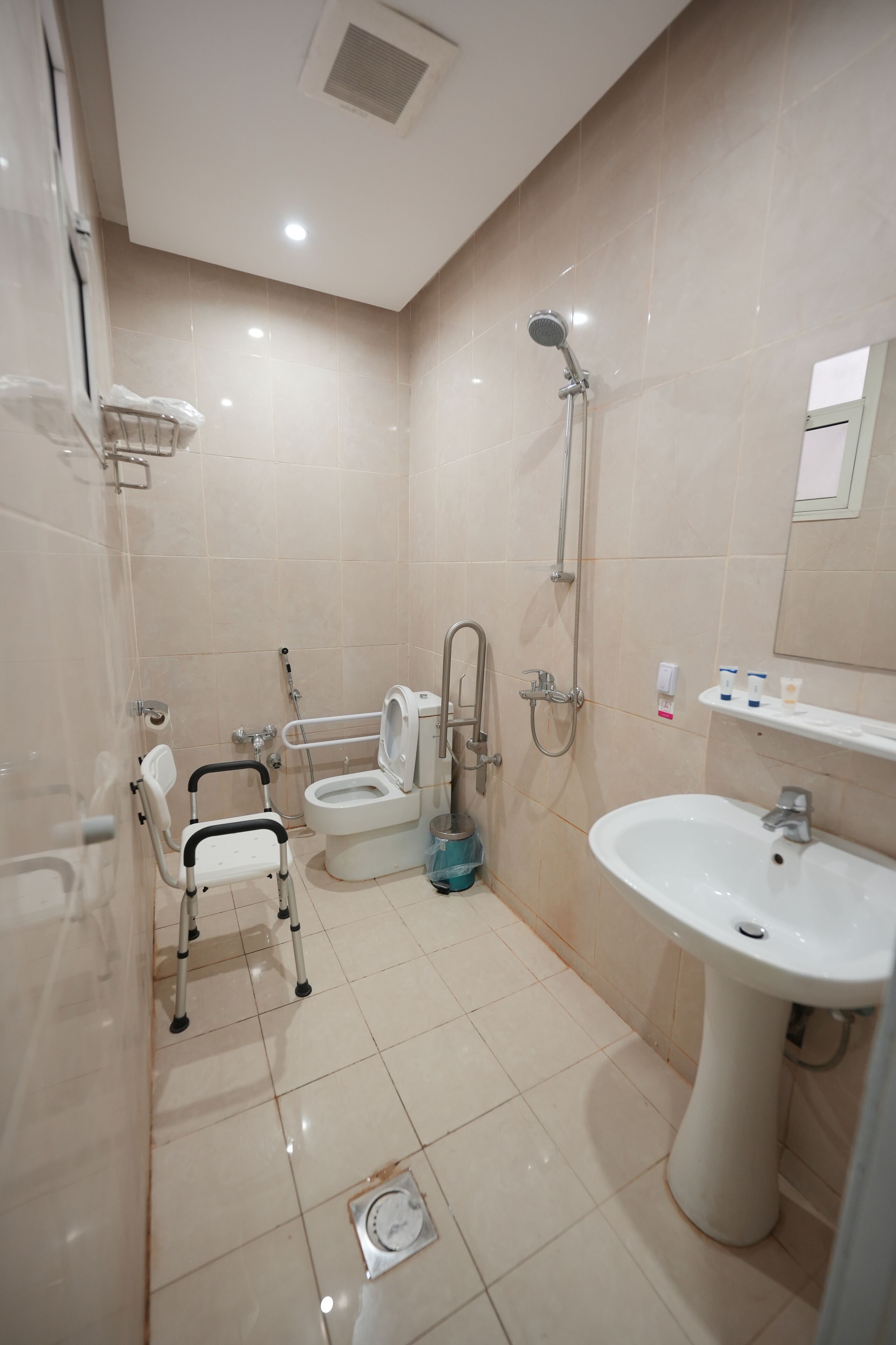 Een moderne badkamer met een toilet aangepast voor rolstoelgebruikers, een douche en een wastafel.
