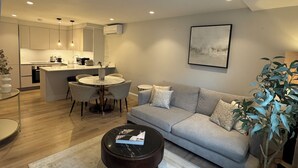 Un salon moderne avec un canapé gris, une table basse et un coin repas comprenant des chaises et une table.