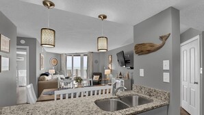 A modern kitchen with granite countertops, stainless steel sink, and pendant lighting. - Stunning 2 bedroom, oceanfront condo (North Topsail Beach)