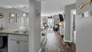 A modern kitchen with granite countertops, a built-in dishwasher, and a dining area with a table and chairs. - Stunning 2 bedroom, oceanfront condo (North Topsail Beach)
