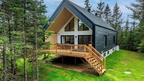 A modern house with a wooden deck, large windows, and a steep roof. - Spa - Pool table | Great Comfort | Chalet Le Mysa (Shannon)