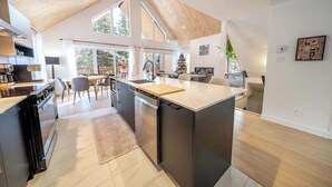 A modern kitchen with a large island, a dining area with chairs, and a view of the outdoors. - Spa - Pool table | Great Comfort | Chalet Le Mysa (Shannon)
