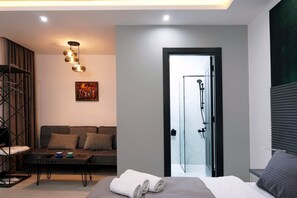A modern bedroom with a glass shower door, a sofa, a coffee table, and a painting on the wall. - Hotel Varla (Kutaisi)