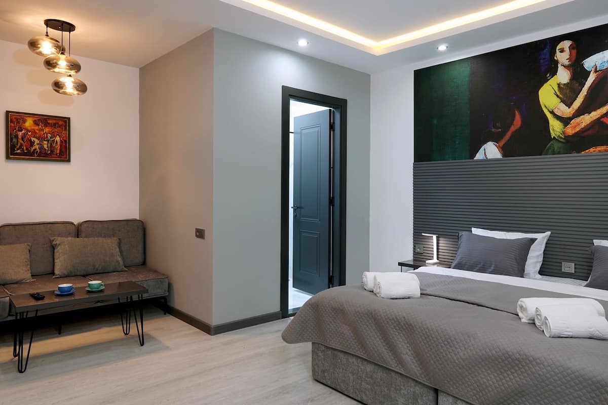 A modern bedroom with a bed, a sofa, a coffee table, and a painting on the wall.