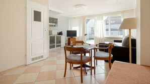 A compact living space with a dining area, kitchenette, and a sofa by a window. - Apartment in Rewal Near the Beach (Rewal)