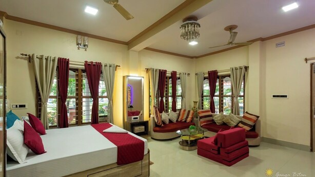 A hotel room with a bed, a sofa, a small table, and a mirror. - Ganga Bitan Family Inn (Uluberiya)