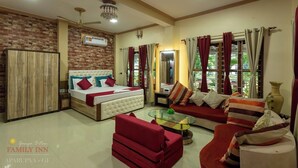 A family room with a bed, sofa, and armchairs, a ceiling fan, and a chandelier. - Ganga Bitan Family Inn (Uluberiya)