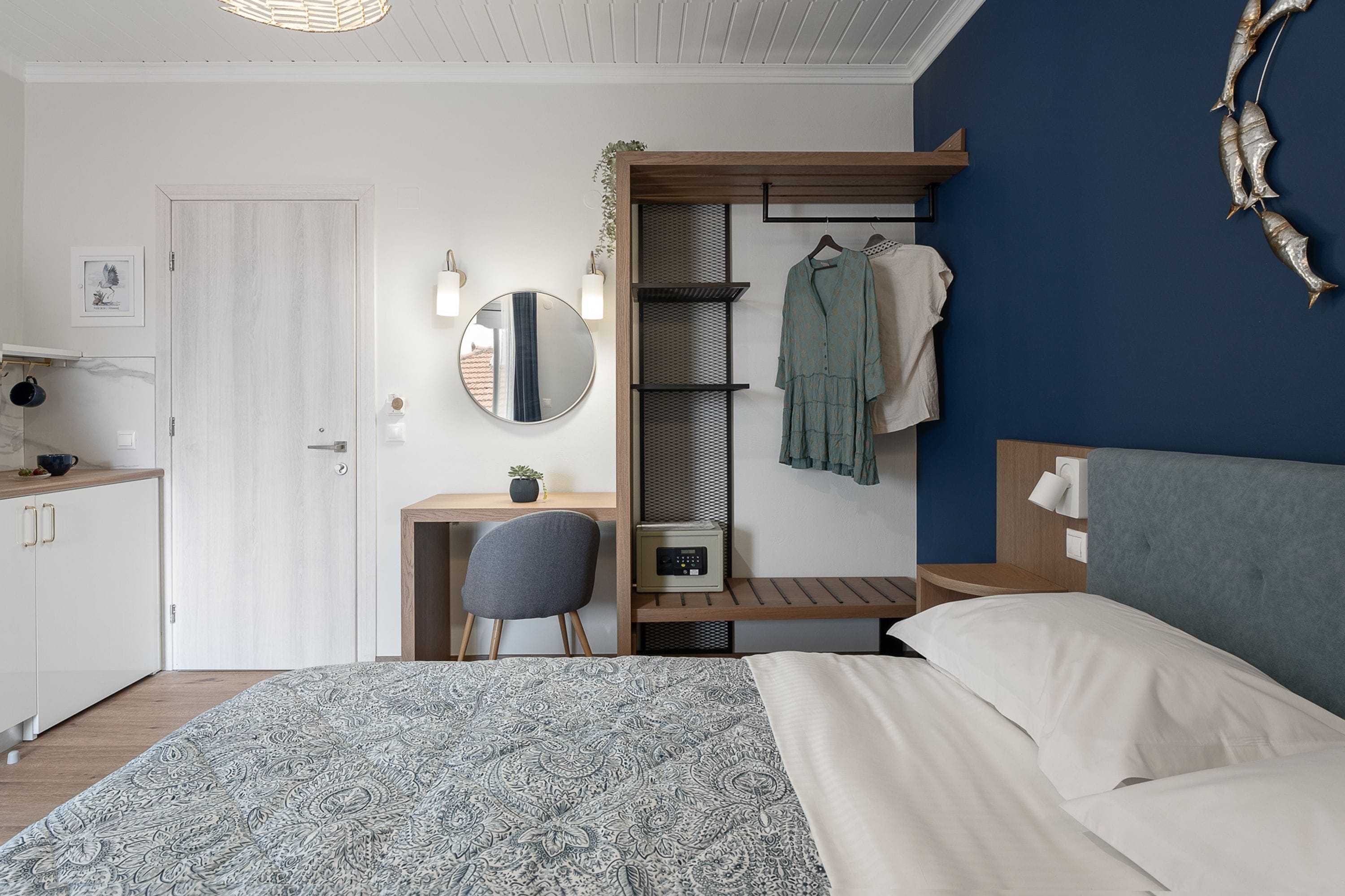 A bedroom with a bed, a desk, a chair, a wardrobe, and a mirror.