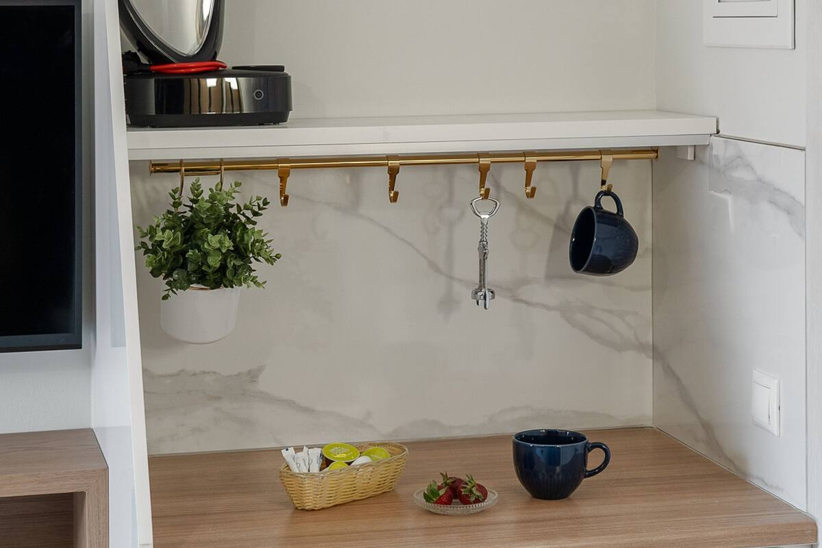A kitchen with a coffee maker, hanging pots, a potted plant, and a fruit bowl.
