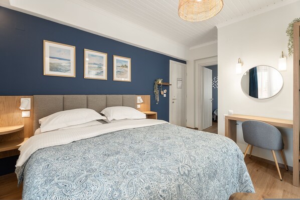 A bedroom with a bed, bedside tables, a desk, and a chair.