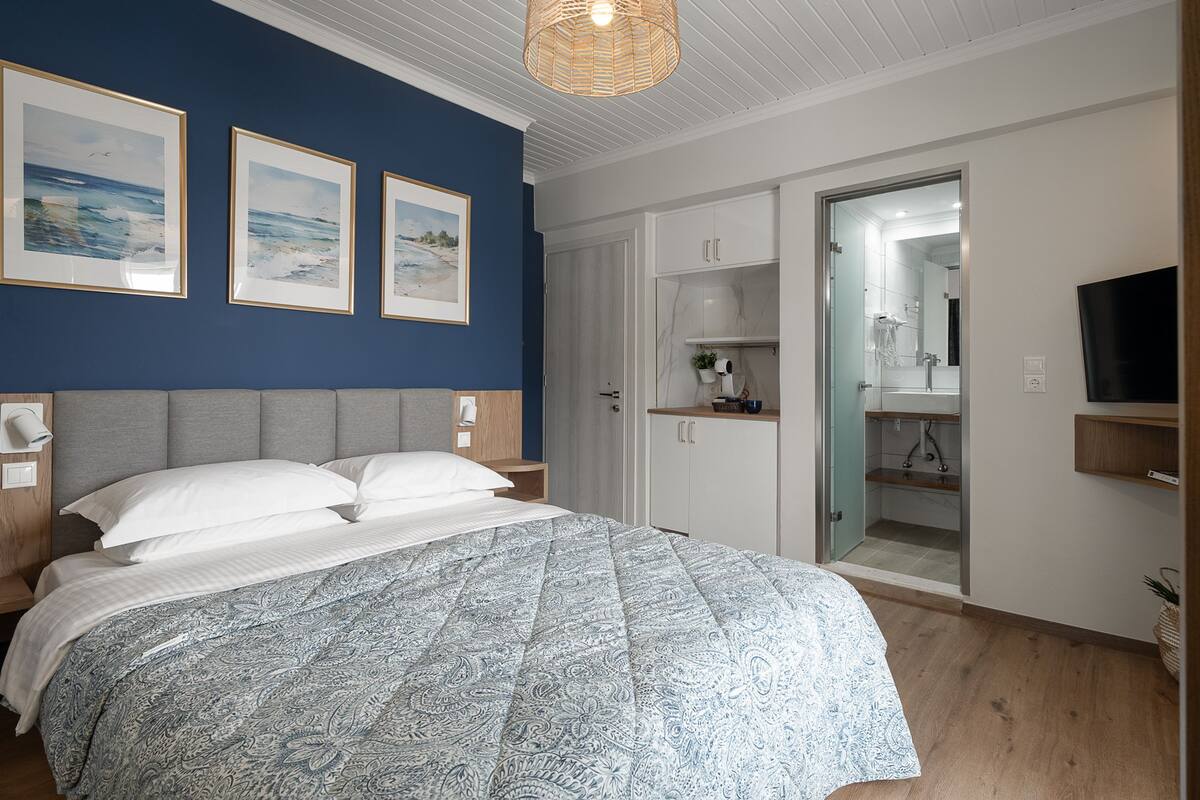 A bedroom with a bed, a wardrobe, a bathroom with a mirror, and a television.