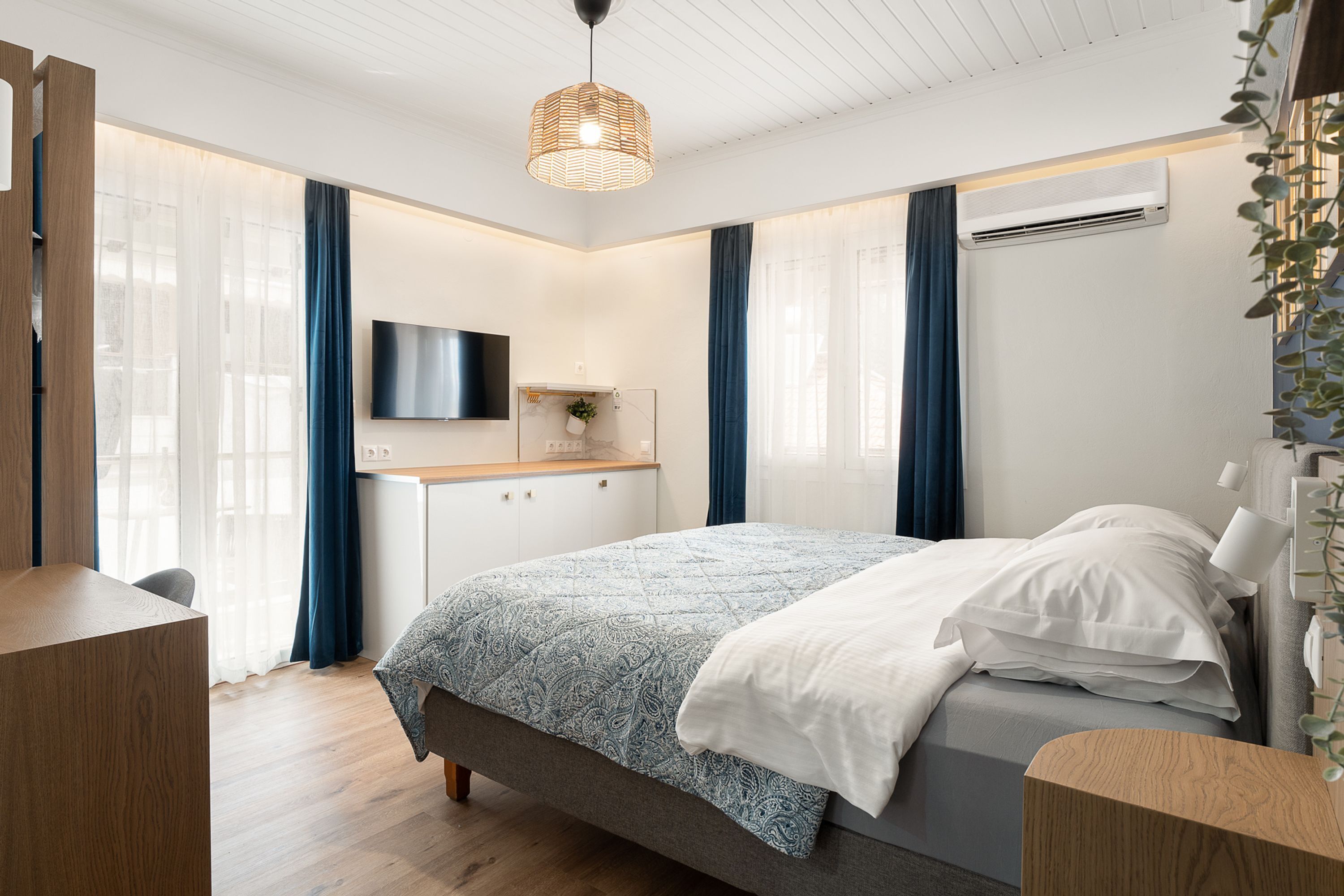 A modern bedroom with a bed, a desk, and a TV.