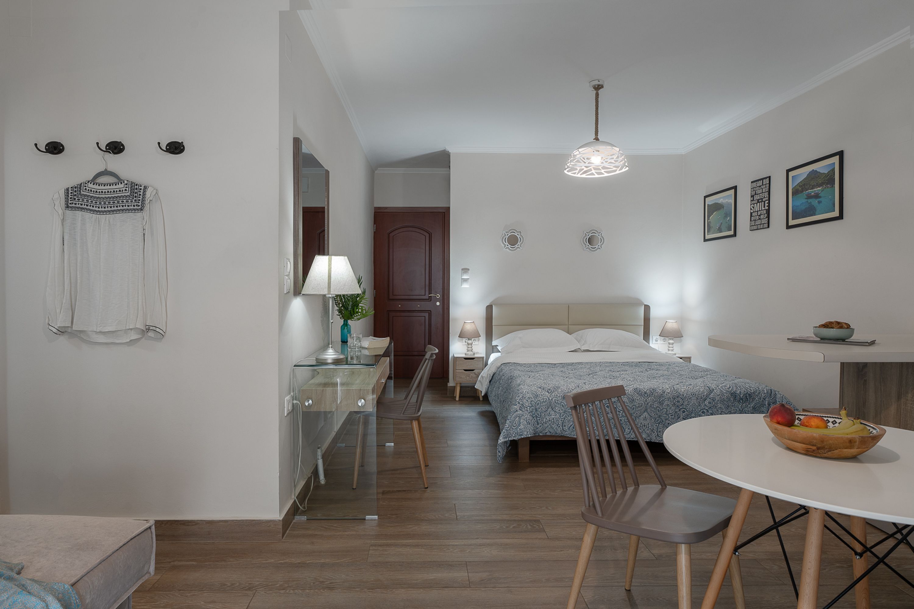 Ein modernes Schlafzimmer mit Bett, Nachttisch, Lampe und einem Essbereich mit Tisch und Stühlen.