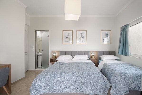 A hotel room with two beds, a desk, and a bathroom visible through a glass door. - Captain's Seafront Apartments (Lefkada)