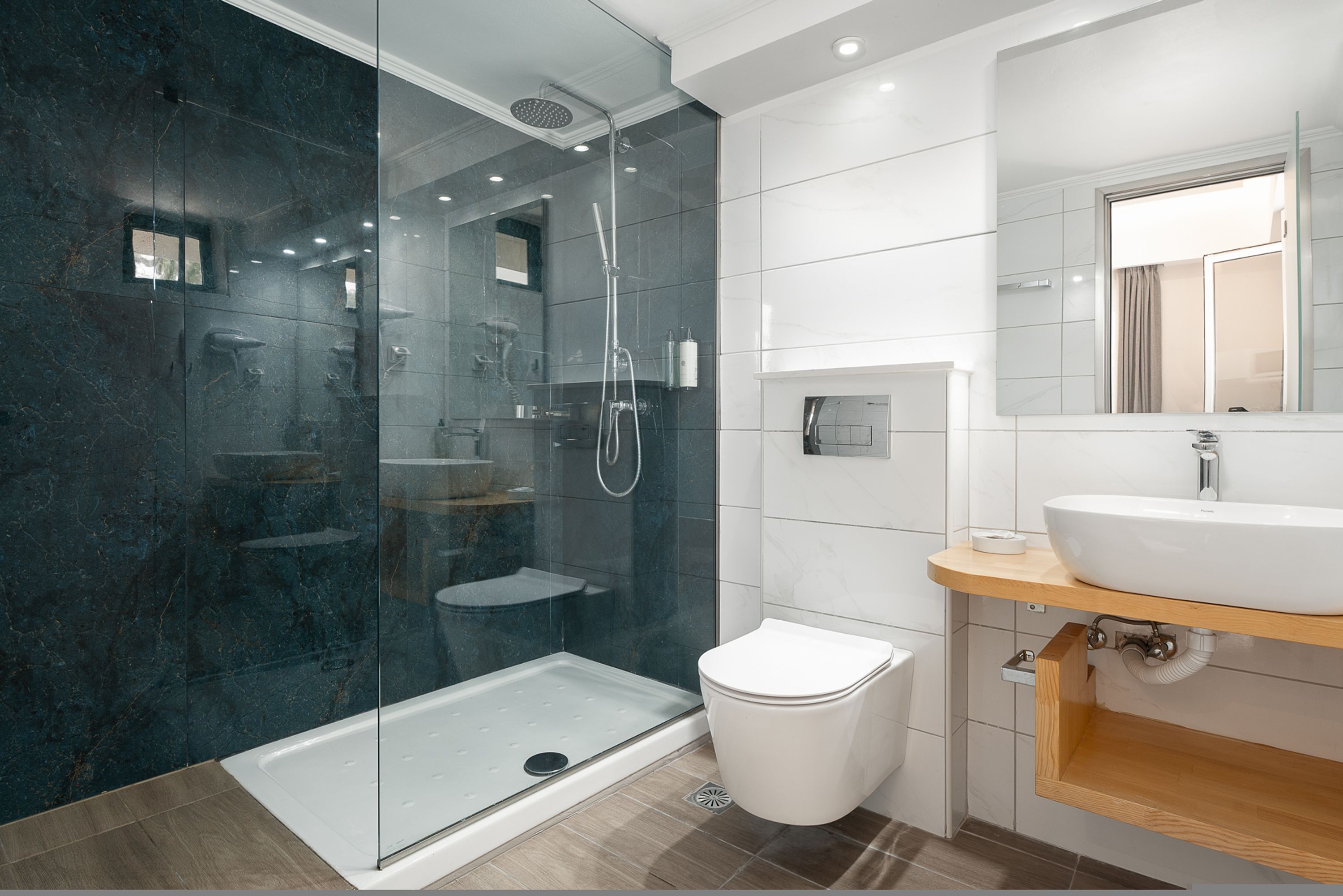 A modern bathroom with a glass-enclosed shower, a white toilet, and a vanity with a mirror.
