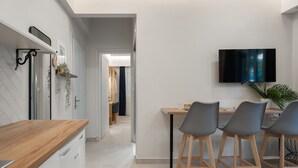A modern kitchen with a wooden countertop, a built-in dishwasher, and a dining area with three grey chairs and a wooden table.