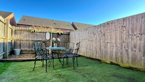 A backyard with a wooden fence, a table with chairs, and a potted plant. - 3 bed cosy home parking & wi-fi (Leicester)