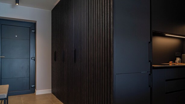 A modern kitchen with dark cabinetry, a built-in oven, and a countertop with a coffee machine. - Pied-à-terre (Zadar)