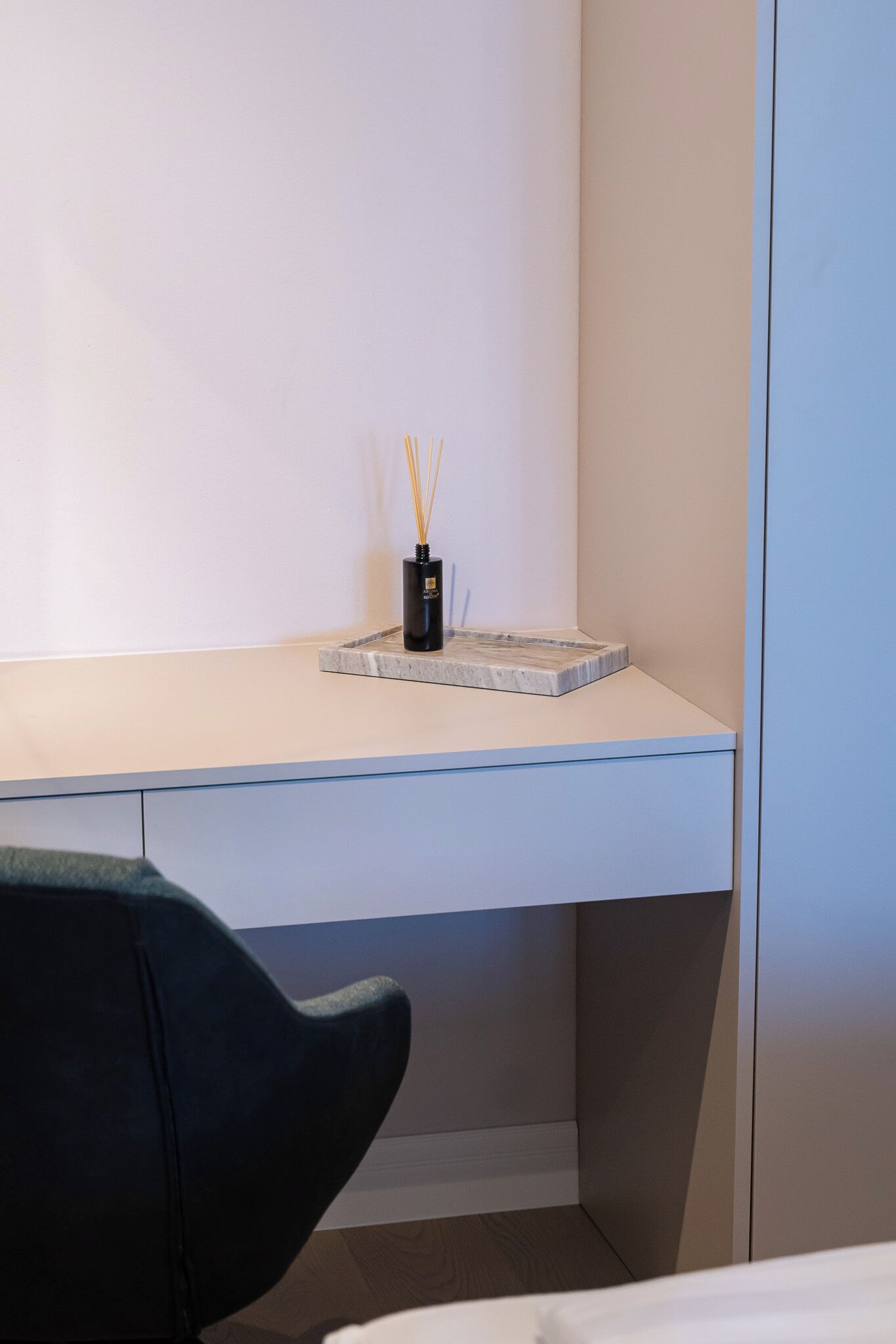 Ein moderner Schreibtisch mit einer schwarzen Vase, die Schilf enthält, einem мраморном Untersetzer und einer kleinen schwarzen Box.