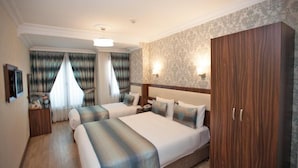 Habitación de hotel con dos camas, un armario, un escritorio y una mesita de noche.