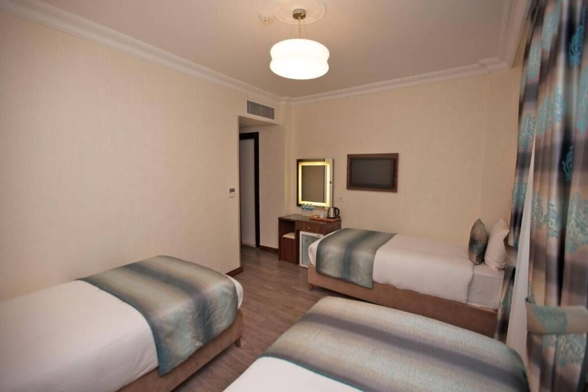 A hotel room with two single beds, a desk with a mirror, and a television.