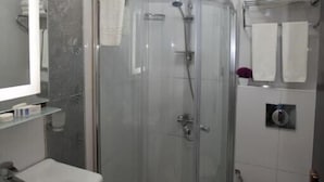 Un baño moderno con cabina de ducha de vidrio, un lavamanos y un inodoro.