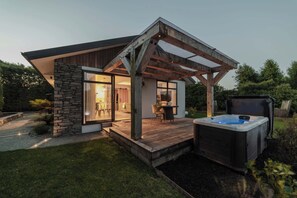 A modern house with a wooden deck, a hot tub, and a stone wall. - Hamptons Retreat - 1BR with Hot Tub (Prebbleton)