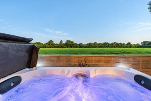A hot tub with a wooden deck and a view of a green field. - Hamptons Cottage | Hot Tub + Fireplace (Prebbleton)