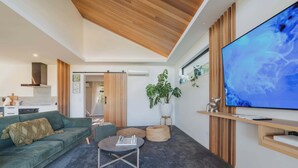 Ein modernes Wohnzimmer mit einem grünen Sofa, einem runden Couchtisch und einem flachbildfernseher an der Wand.