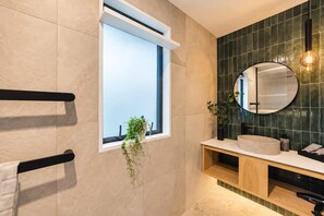 Une salle de bain moderne avec une grande fenêtre, un miroir rond et un meuble-lavabo en bois.
