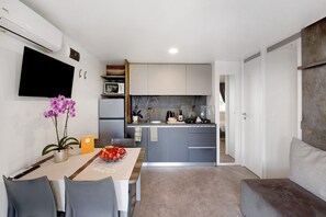 Una cucina moderna con mobili grigi, un televisore a schermo piatto e un'area pranzo con tavolo apparecchiato per due.