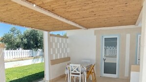 An outdoor patio area with a wooden ceiling, a table with chairs, and a door leading to a covered space. - Cozy little house Otranto Baia dei Turchi - pet friendly. 7 (Puglia)