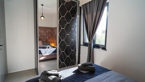 A modern bedroom with a large bed, a sliding door, and a view of another room. - La Vista Azure (Sukosan)