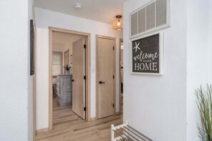 A hallway with wooden doors, a welcome sign, and a plant. - Oceanside with Pool Hot Tub and Updated Interior! (Corolla)