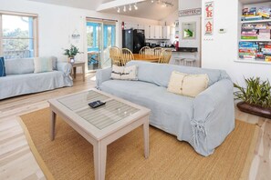 A living room with two sofas, a coffee table, and a kitchen in the background. - Oceanside with Pool Hot Tub and Updated Interior! (Corolla)