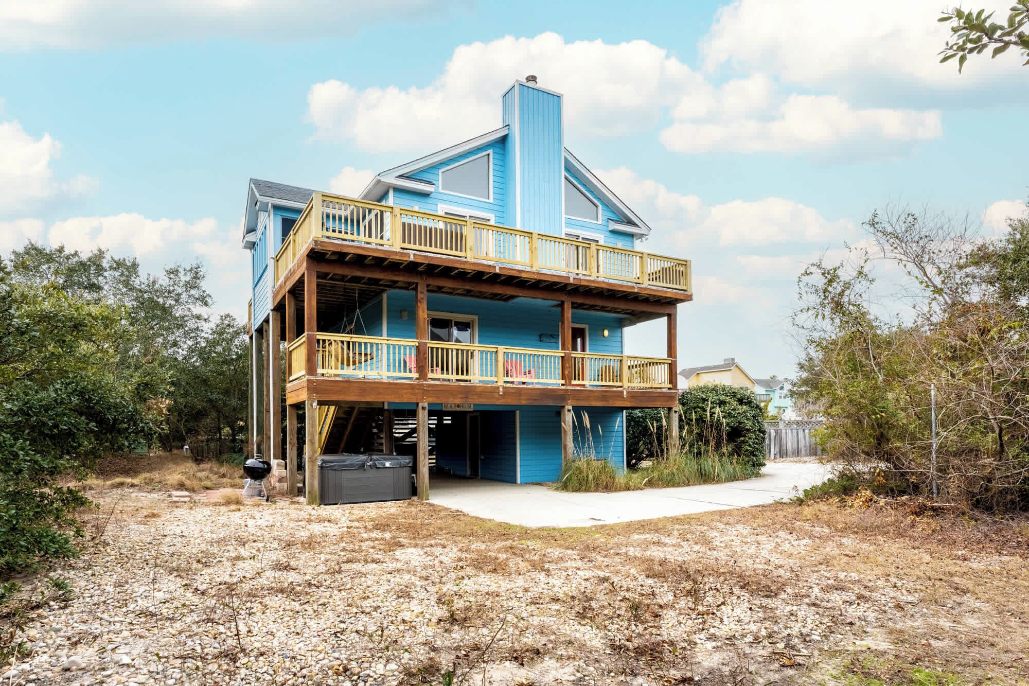 A two-story house with a wooden deck and a covered porch.