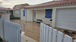 A residential property with a tiled roof, a fenced patio, and a garage door.
