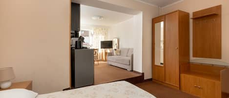 A hotel room with a bed, a desk with a computer, a TV, and a wardrobe.