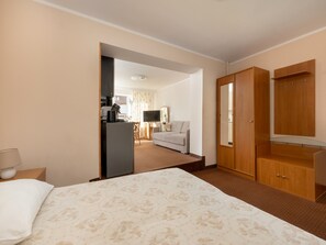 Una camera d'albergo con un letto, una scrivania con un computer, una televisione e un armadio.