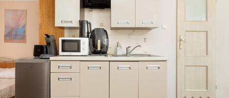A compact kitchenette with a microwave, coffee maker, and sink.