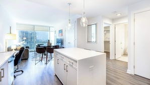 A modern kitchen with a central island, a dining area with chairs, and a large window providing a view. - Luxury Modern Apt with Pool (Stamford, CT)