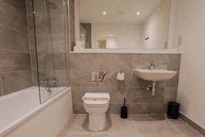 Ein modernes Badezimmer mit einer Duschkabine, einer Toilette, einem Waschbecken und einem Spiegel.