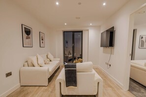 A modern living room with a sofa, a coffee table, and a TV mounted on the wall.