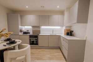 Una cocina compacta con electrodomésticos modernos, un comedor con una silla y una pequeña mesa.