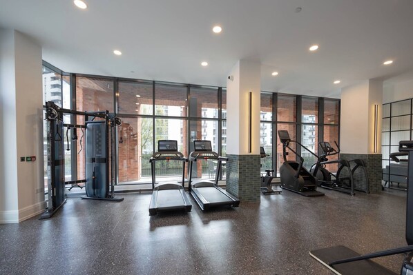 A modern gym with treadmills, elliptical machines, and weightlifting equipment.