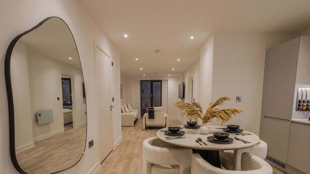 A modern dining area with a round table, white chairs, and a large mirror on the wall. - Bianco Suite 2BR with City Views (Greater Manchester)