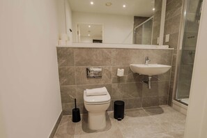 Een moderne badkamer met toilet, wastafel en douche.