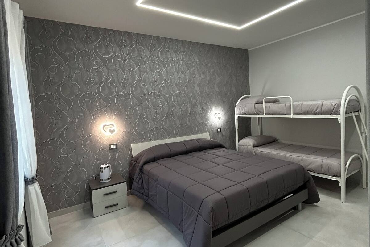 A modern bedroom with a bunk bed, a bedside table with a lamp, and a patterned wall.