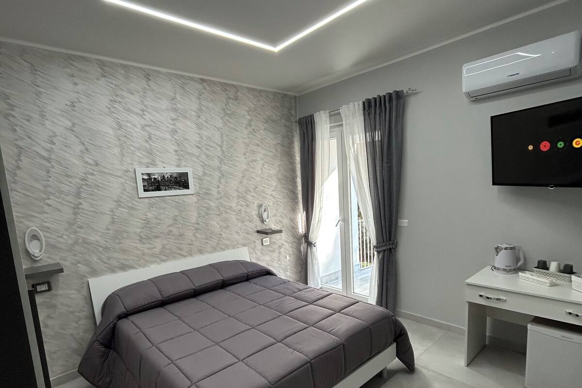 A modern bedroom with a bed, a desk, and a television.