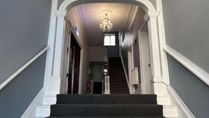 Eine prächtige Treppe mit einer Chandelier, weißem Stuck und einem dunklen Teppichboden.